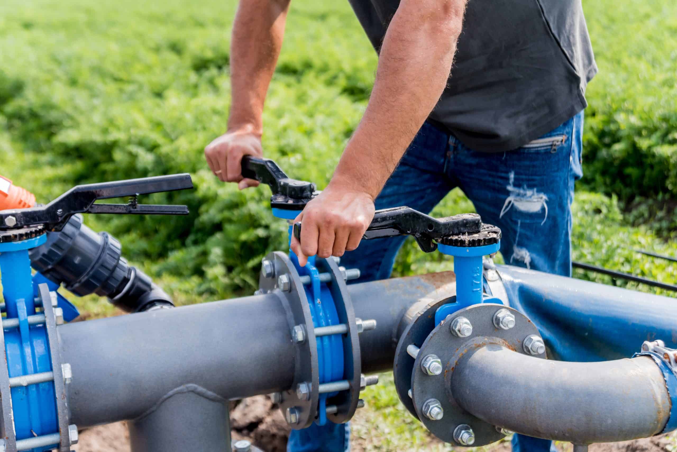 Drip Irrigation System. Water Saving Drip Irrigation System Being Used In A Young Carrot Field. Worker Opens The Tap. Agricultural Background