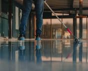The Worker Applies Gray Epoxy Resin To The New Floor
